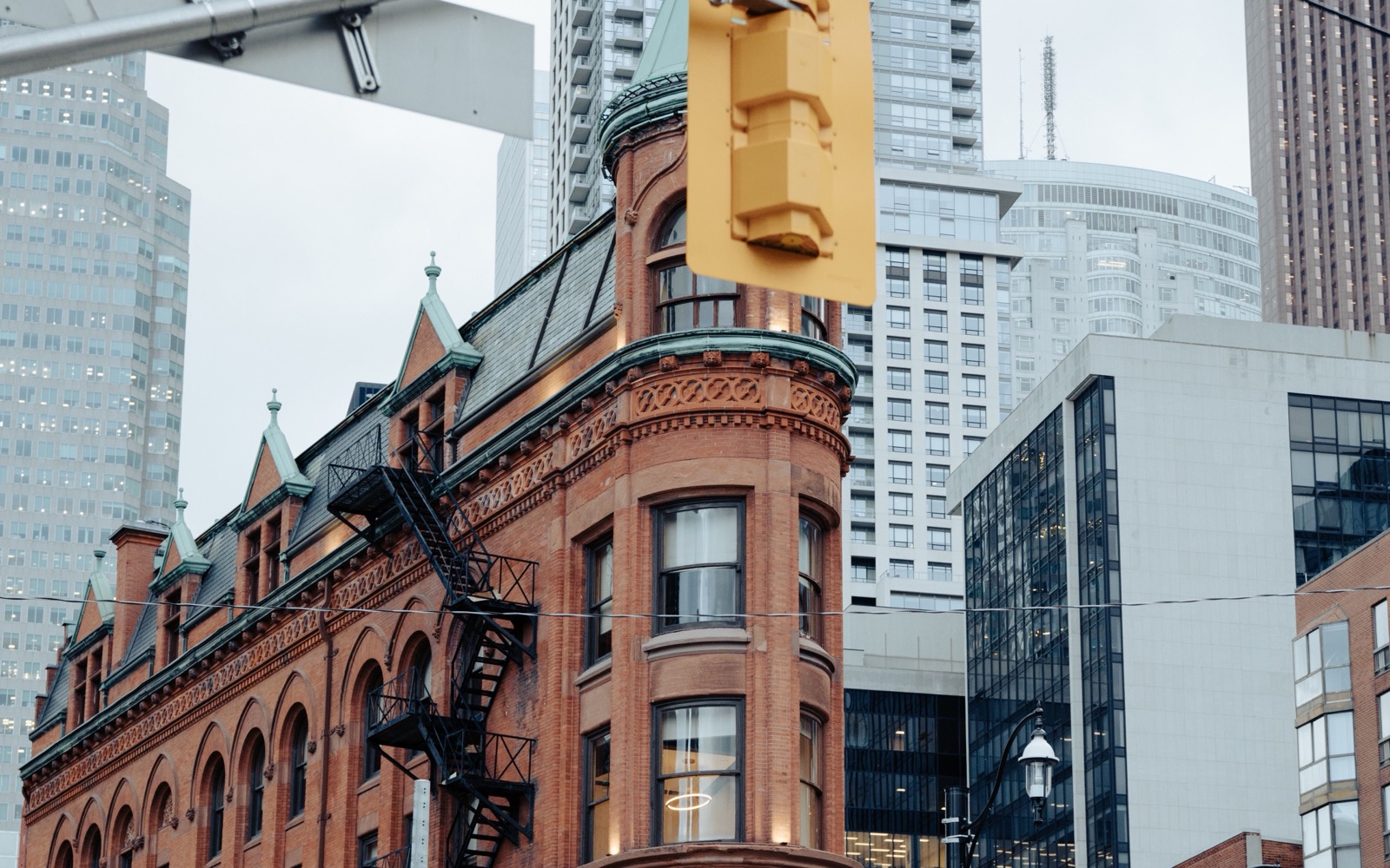 Toronto's red-brick Flatiron building on a downtown corner, with glass office towers behind it